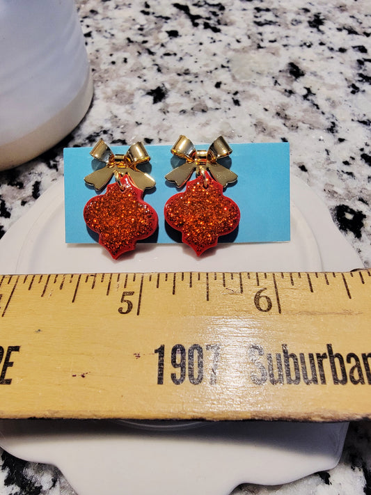 Glittery red dangles with gold bow top